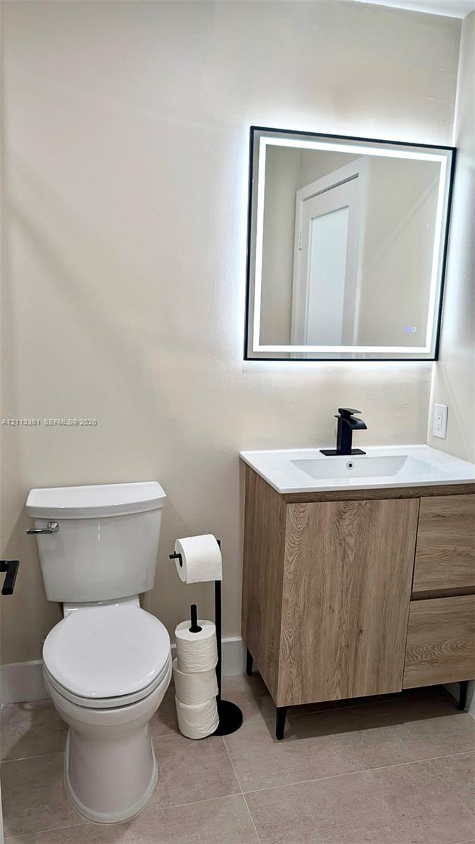 Walk-in shower featuring a sliding glass enclosure with matte black hardware, herringbone-patterned wall tile, pebble-style floor tiling, and a rainfall showerhead