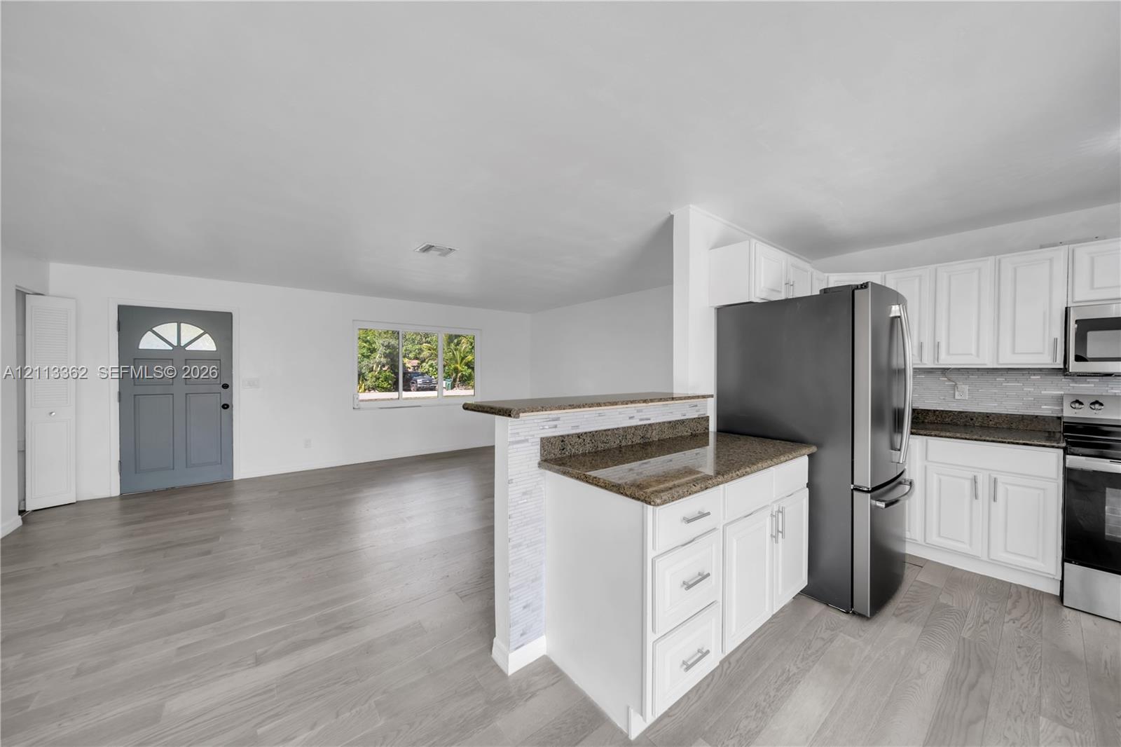 Kitchen featuring white cabinetry, stone-finish countertops, stainless steel appliances, wood-finish flooring, and a half-wall peninsula