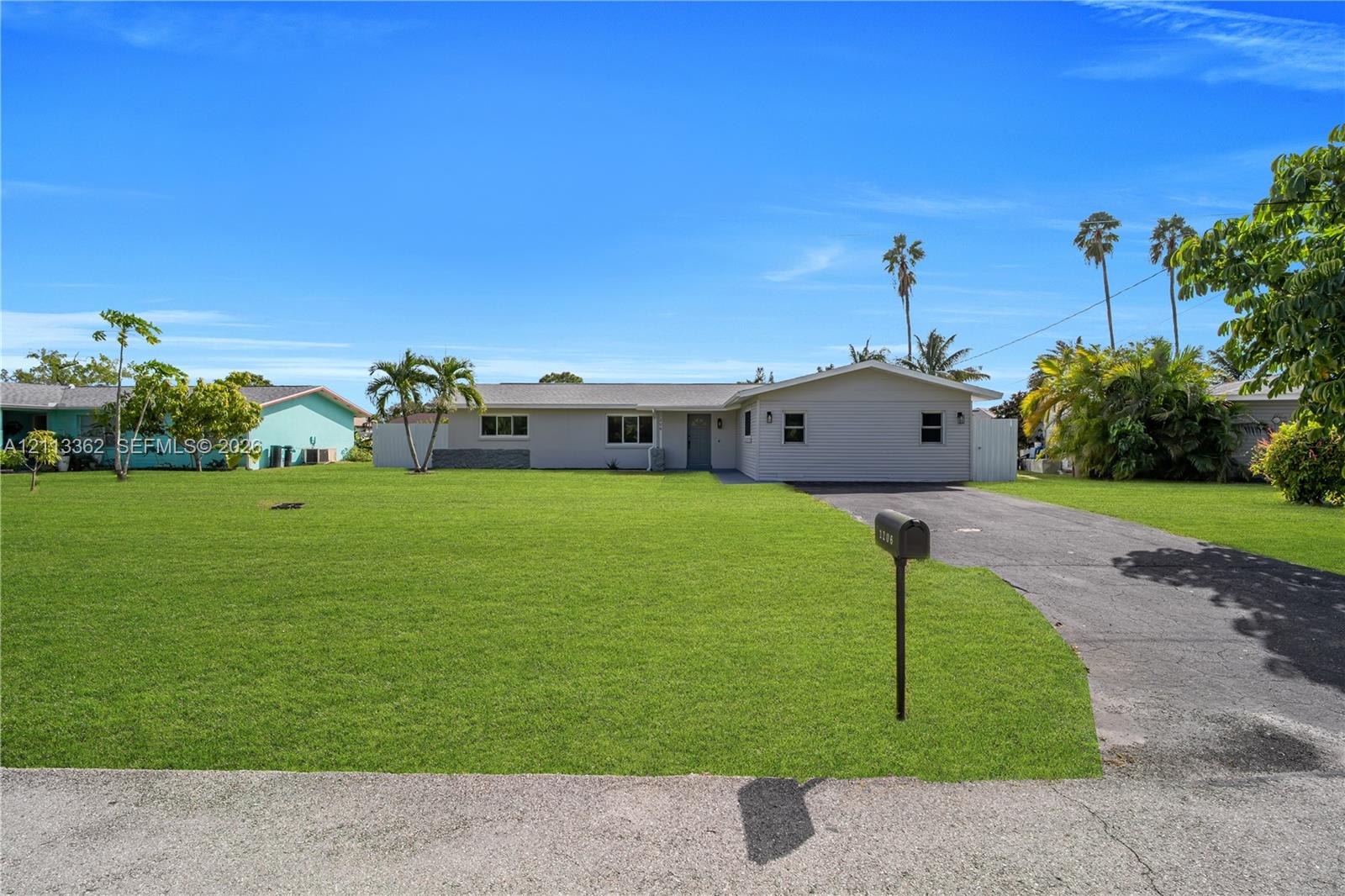 Single-story exterior featuring a neutral-toned facade, an attached driveway, and expansive lawn space