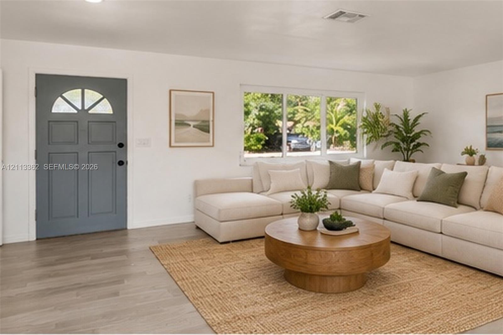 Neutral interior featuring wood-finish flooring, white walls, and a charcoal-toned entry door with a multi-pane arched transom window Neutral interior featuring wood-finish flooring, white walls, and a charcoal-toned entry door with a multi-pane arched transom window