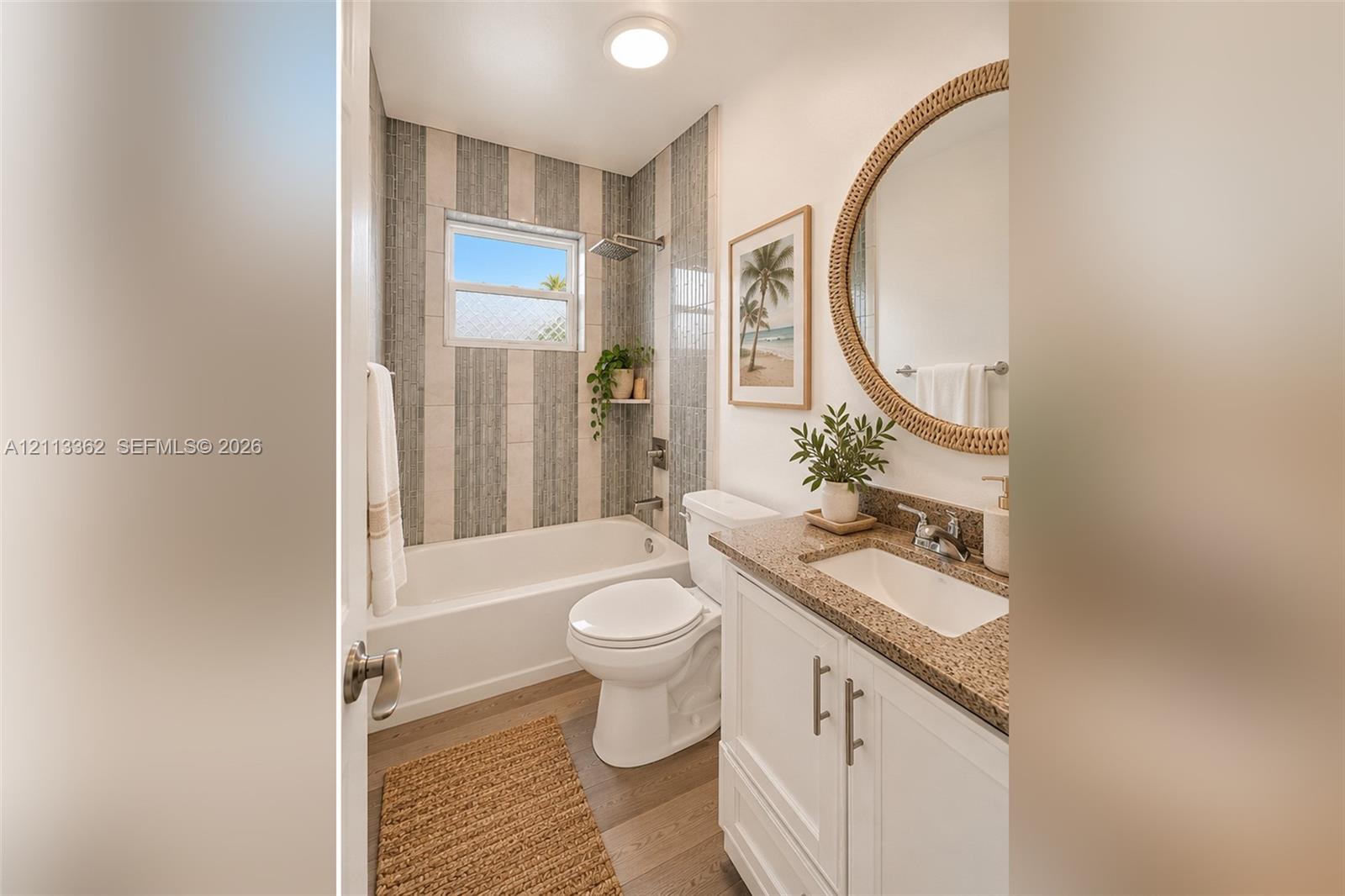 Bathroom featuring a white vanity with a speckled countertop, integrated sink, vertical-tile tub surround, and wood-finish flooring