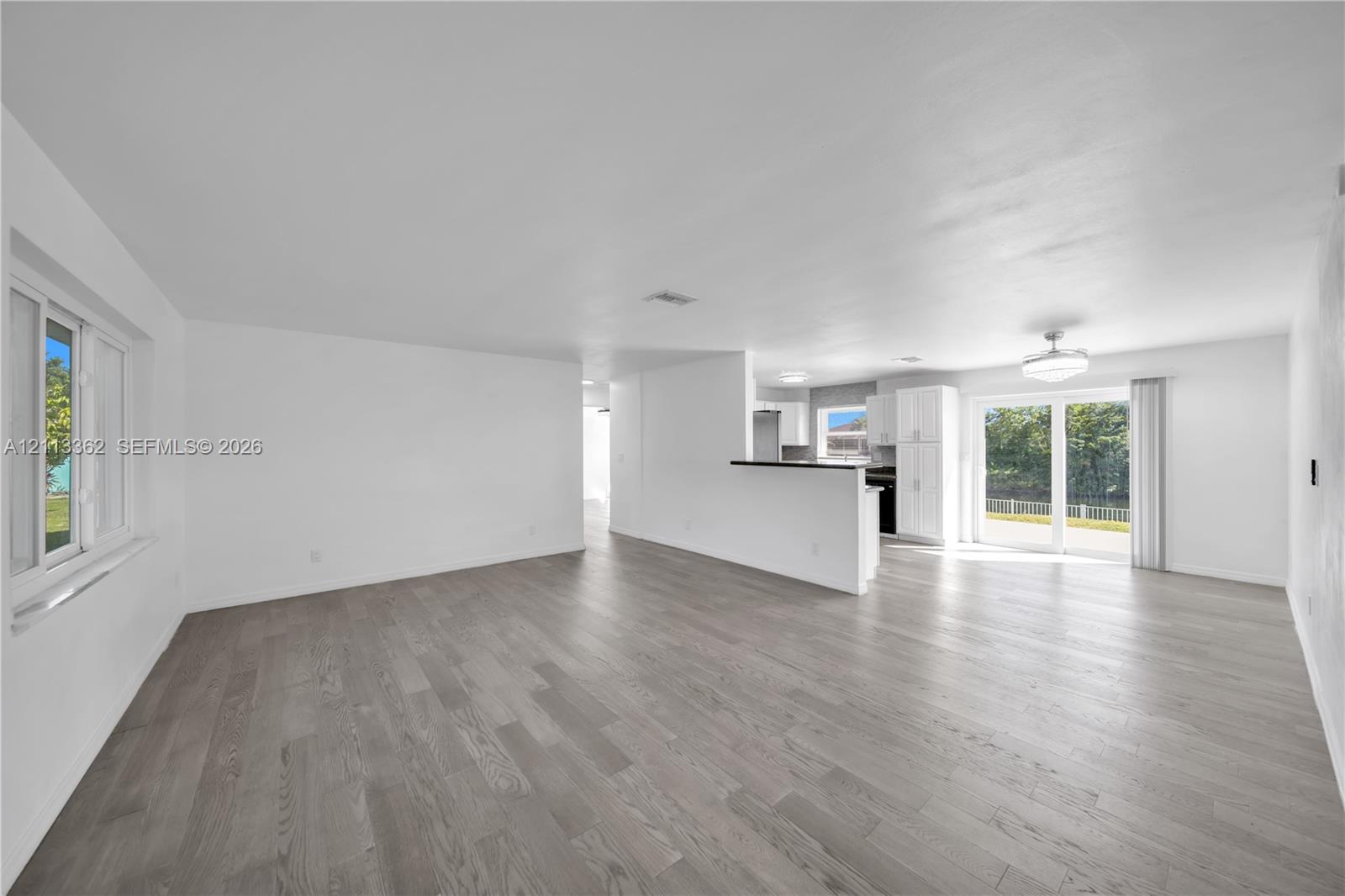 Open-concept area featuring wood-finish flooring, sliding glass doors, white cabinetry, a built-in counter, and neutral wall tones