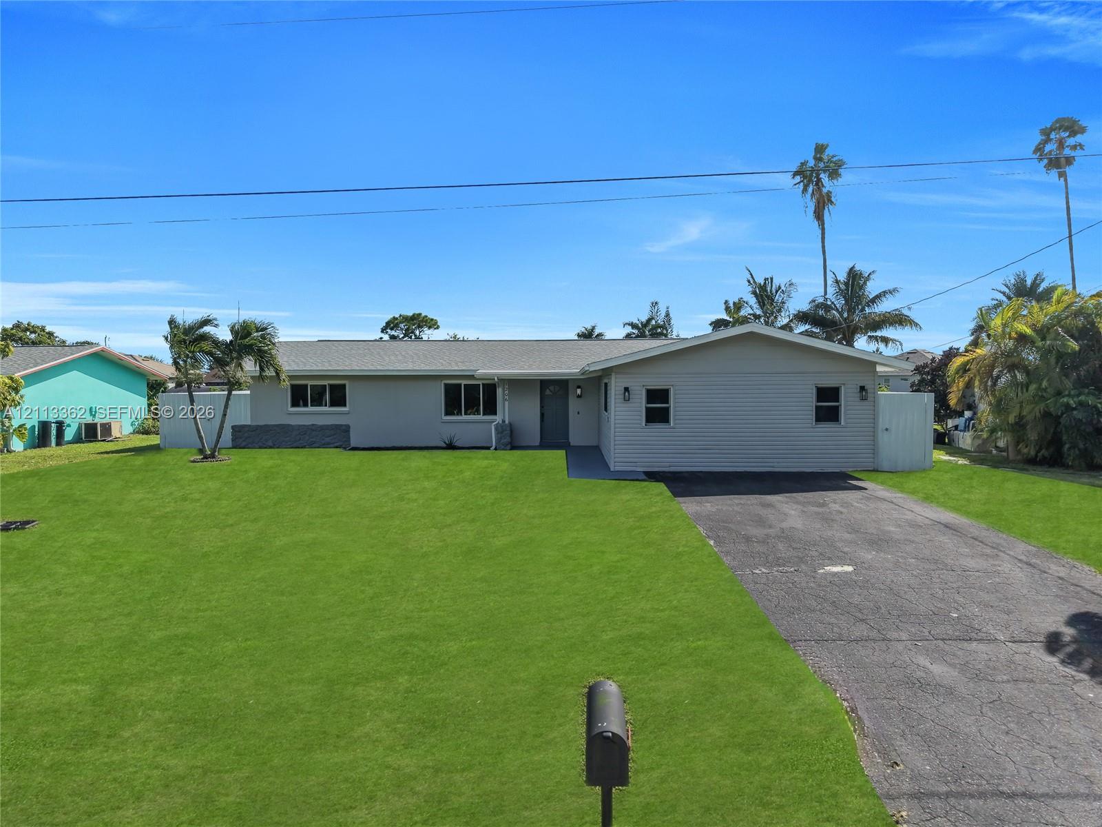 Single-story residence featuring horizontal lap siding, a low-pitch roofline, an expansive front lawn, and an asphalt driveway
