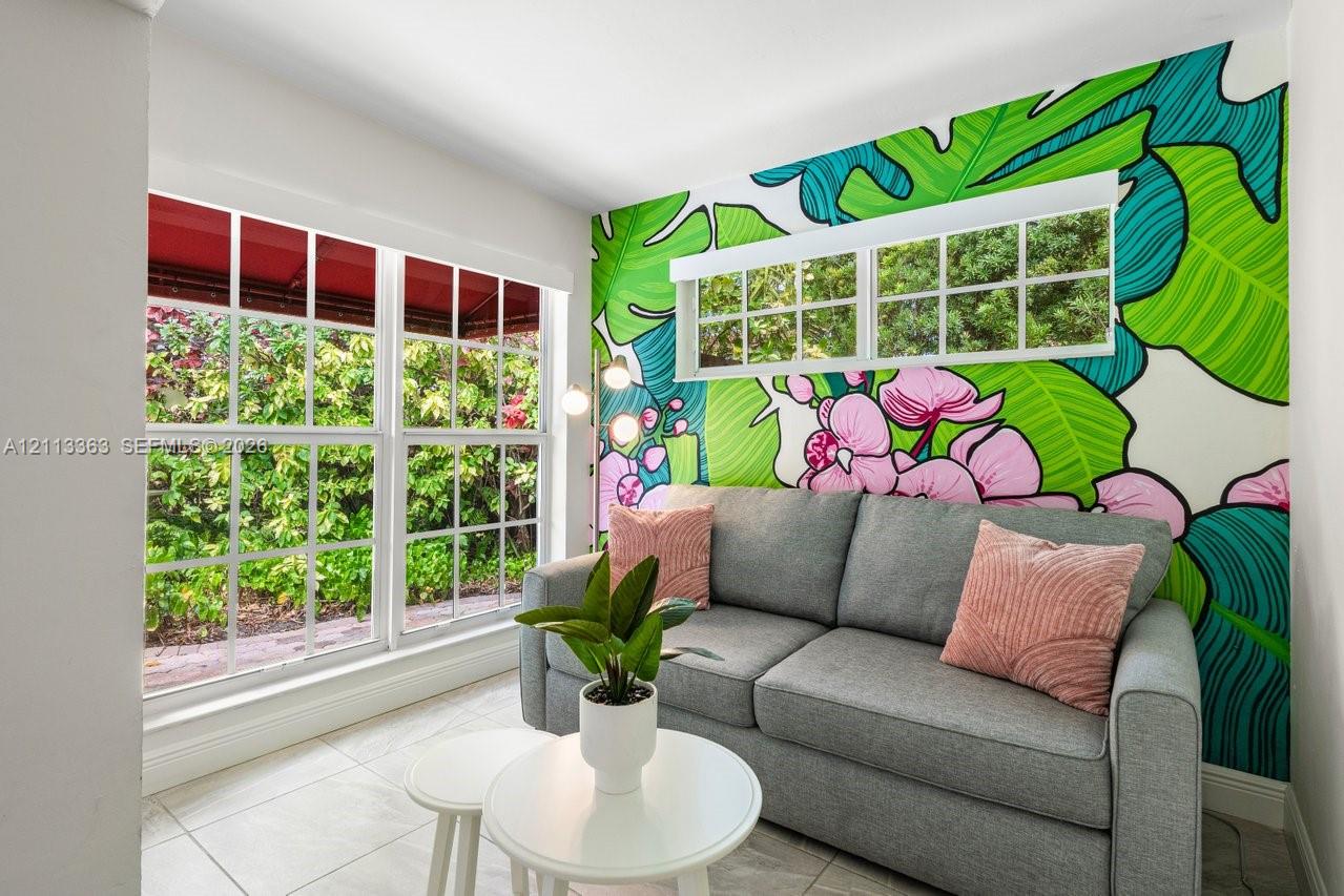 Large grid-pane windows with natural light, tiled flooring, and a decorative mural wall feature