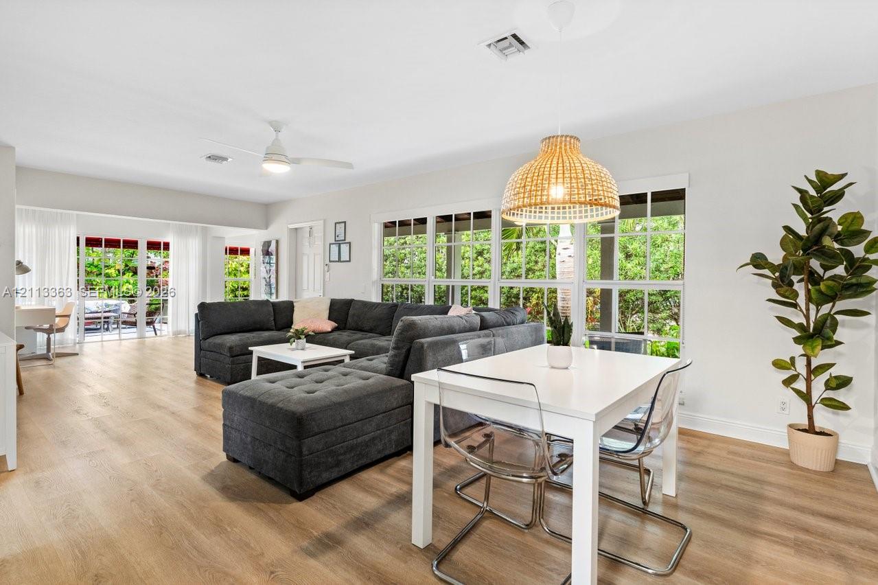 Open-concept space featuring wood-finish flooring, multi-pane windows, a woven dome pendant light, and sliding glass doors