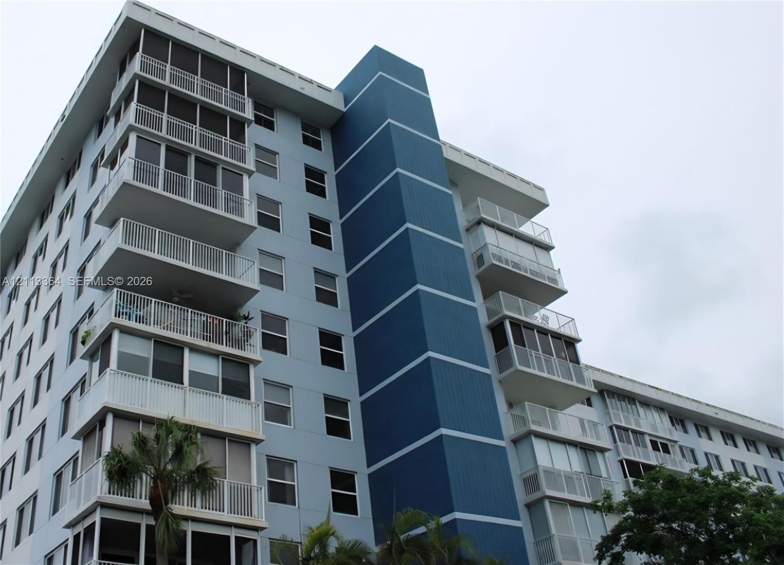 Multi-story residential building featuring a blue facade, vertical accent detailing, and private screened-in balconies