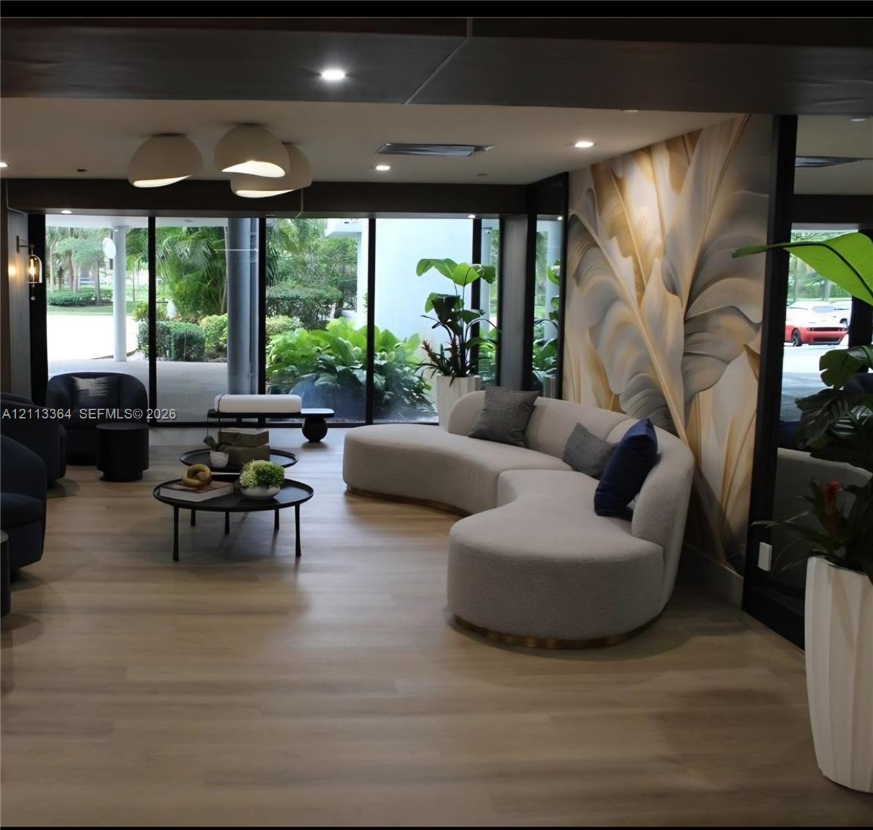Floor-to-ceiling glass wall, wood-finish flooring, recessed lighting, sculptural pendant lighting, and oversized botanical-patterned wall mural