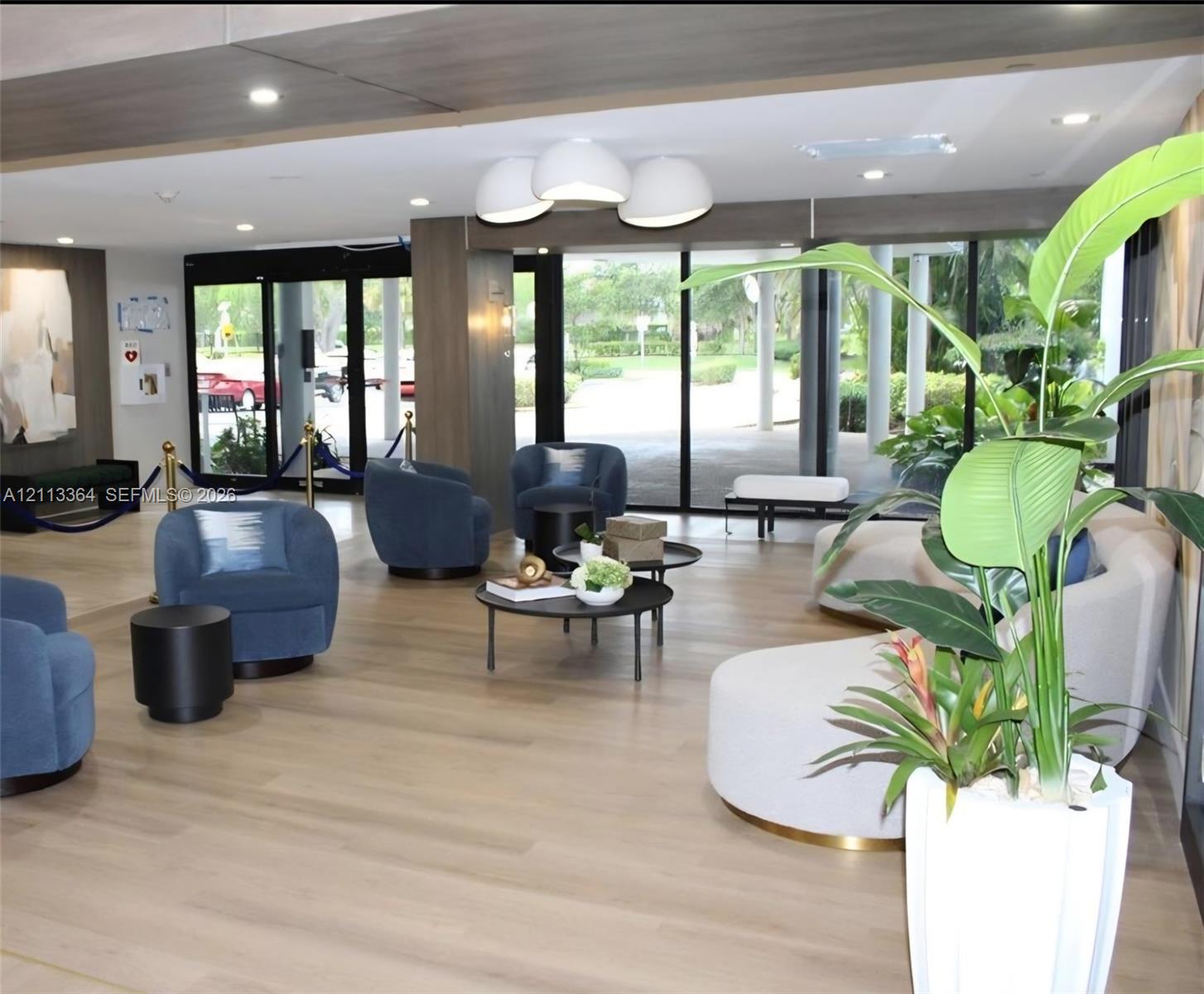 Reception area featuring wood-finish flooring, recessed lighting, wood-paneled accents, and floor-to-ceiling glass entrance doors