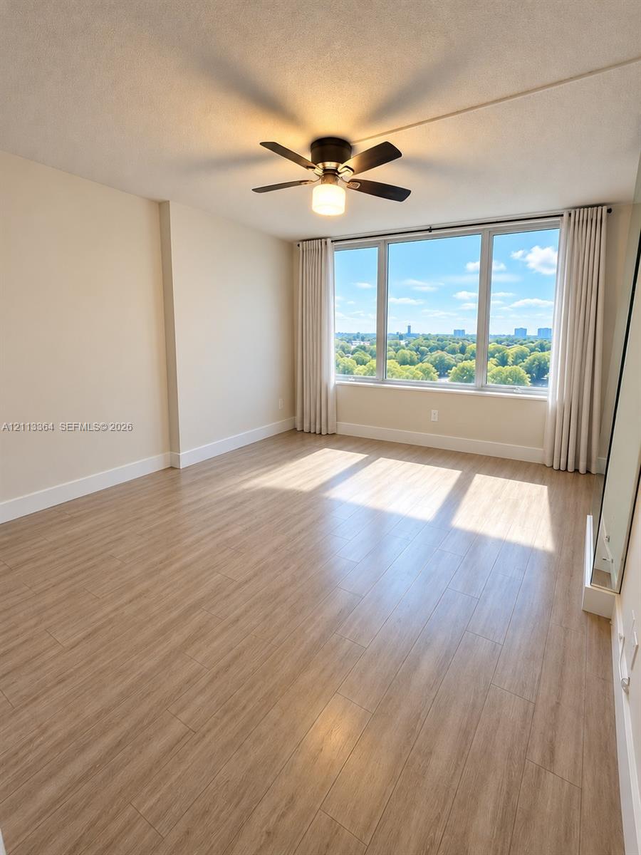 Expansive floor-to-ceiling windows, wood-finish flooring, and a ceiling-mounted light fixture with an integrated fan