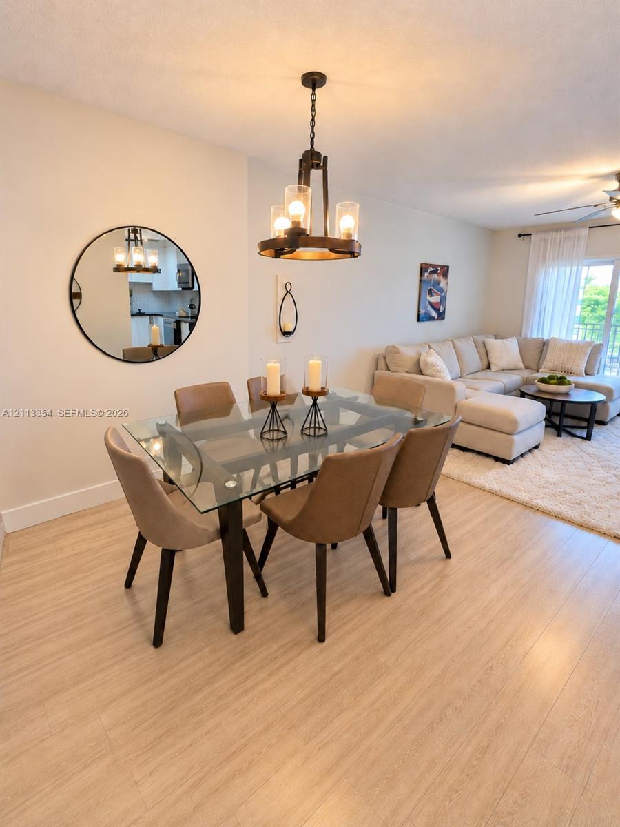 Wood-finish flooring, metal industrial-style chandelier, and round wall-mounted mirror