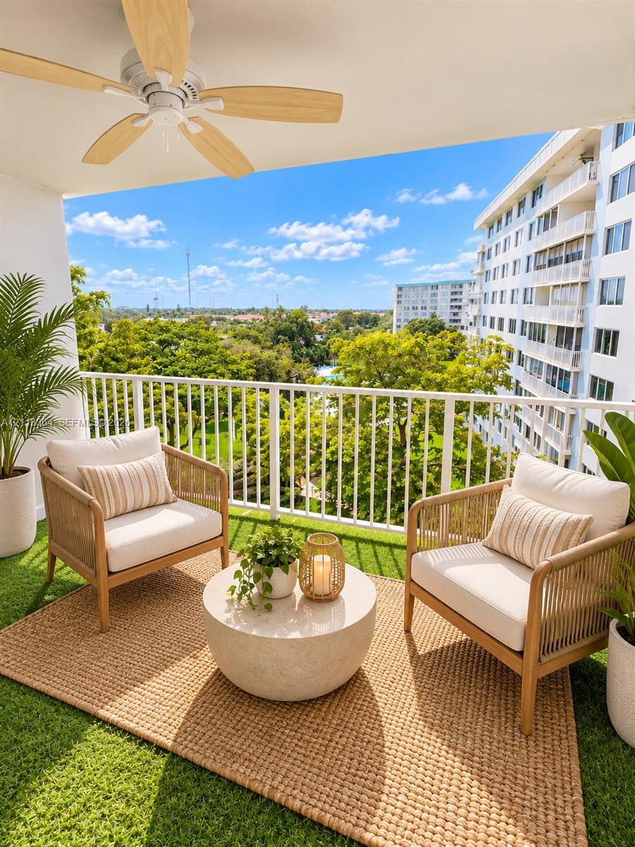 Covered balcony featuring artificial turf flooring, a white metal railing, and a ceiling-mounted paddle fan