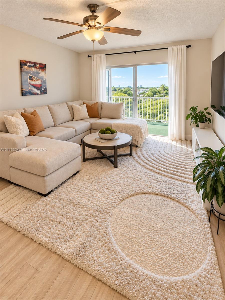 Living area featuring wood-finish flooring, a ceiling fan with integrated lighting, and a sliding glass door providing access to a balcony