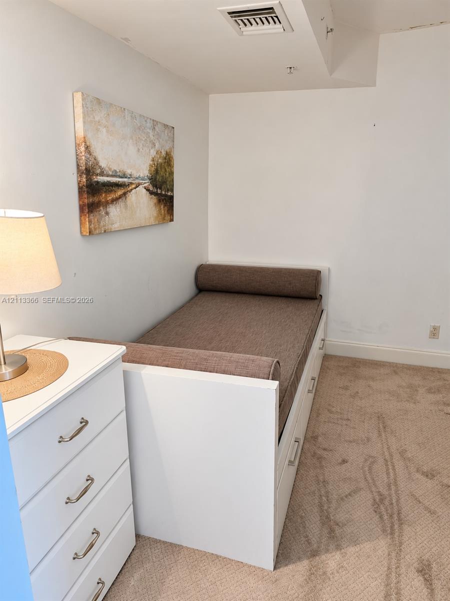 Built-in white platform bed frame featuring integrated under-bed storage drawers and neutral wall-to-wall carpeting