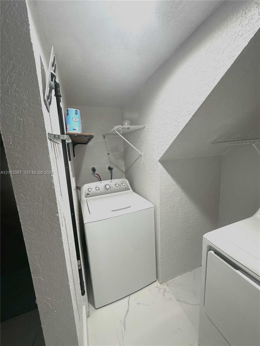 Laundry area featuring stone-finish flooring and built-in wire shelving