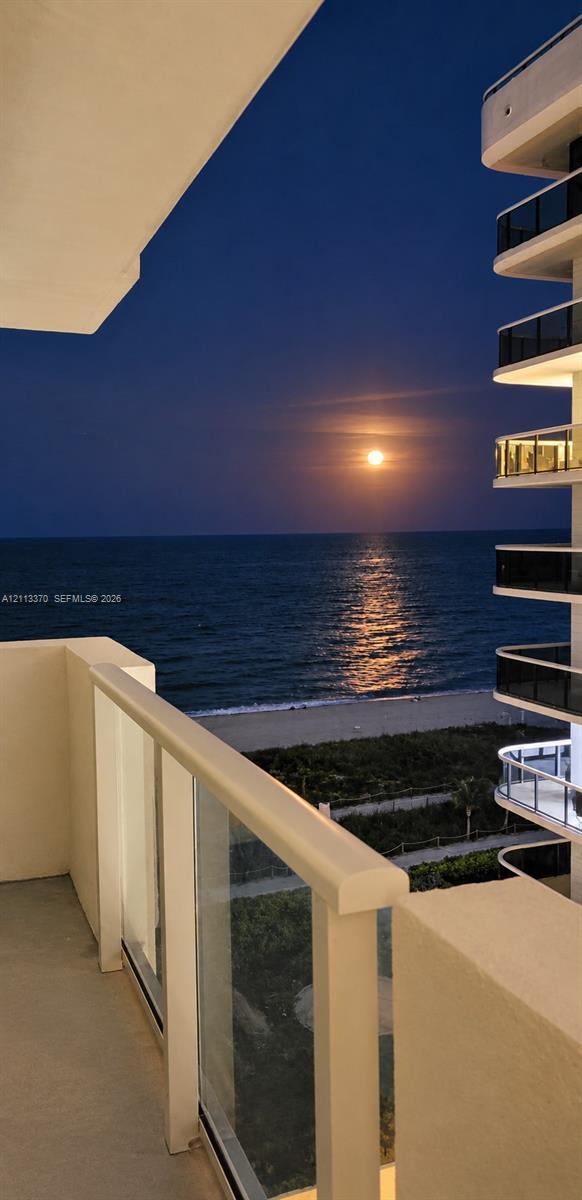 Covered balcony with glass panel railing overlooking the ocean and coastline