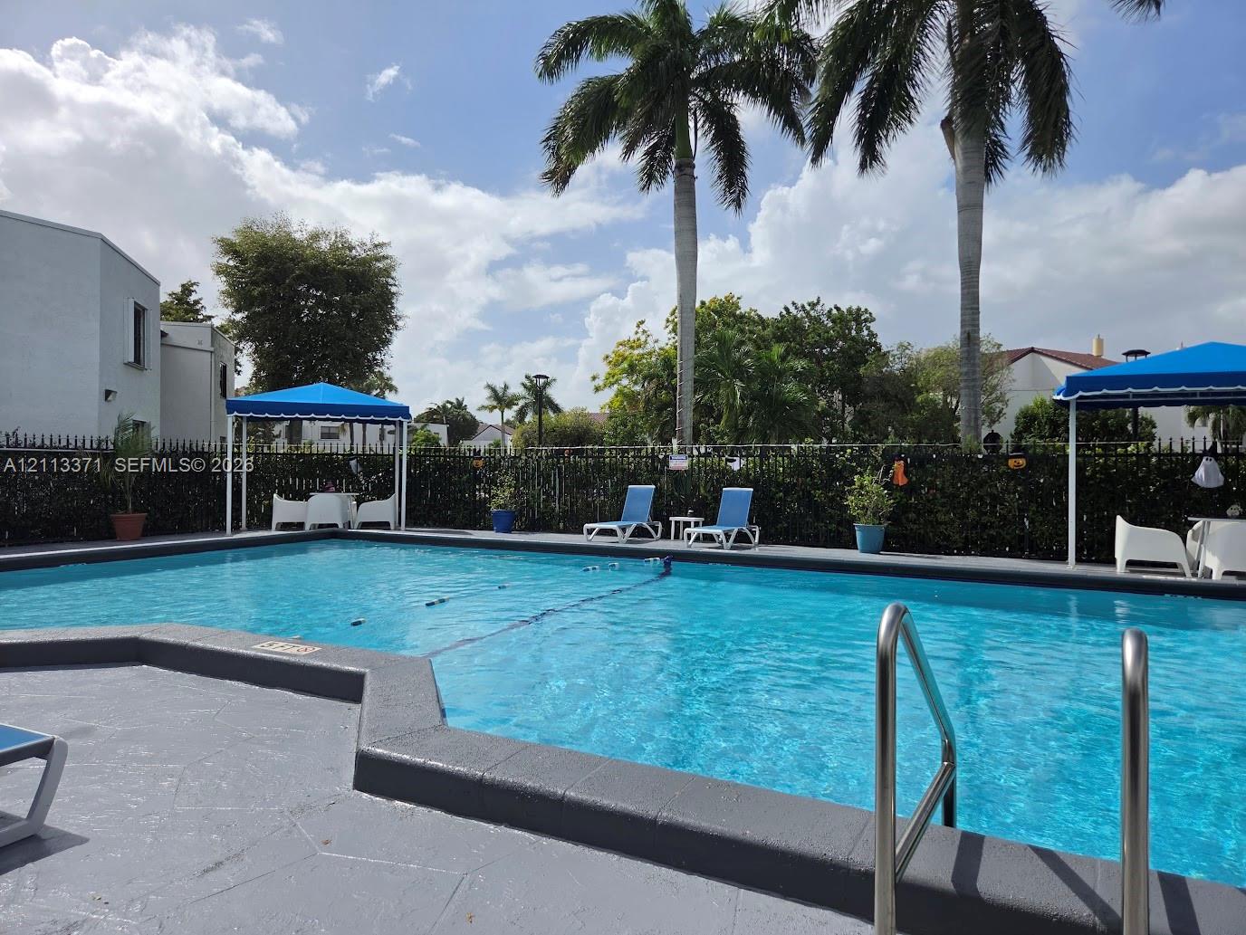 Swimming pool with a paved deck, metal railings, and dual poolside shade structures