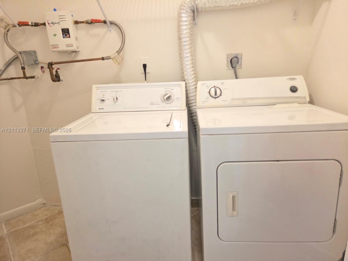 Laundry area featuring a tankless water heater, dedicated washer and dryer hookups, and ceramic tile flooring