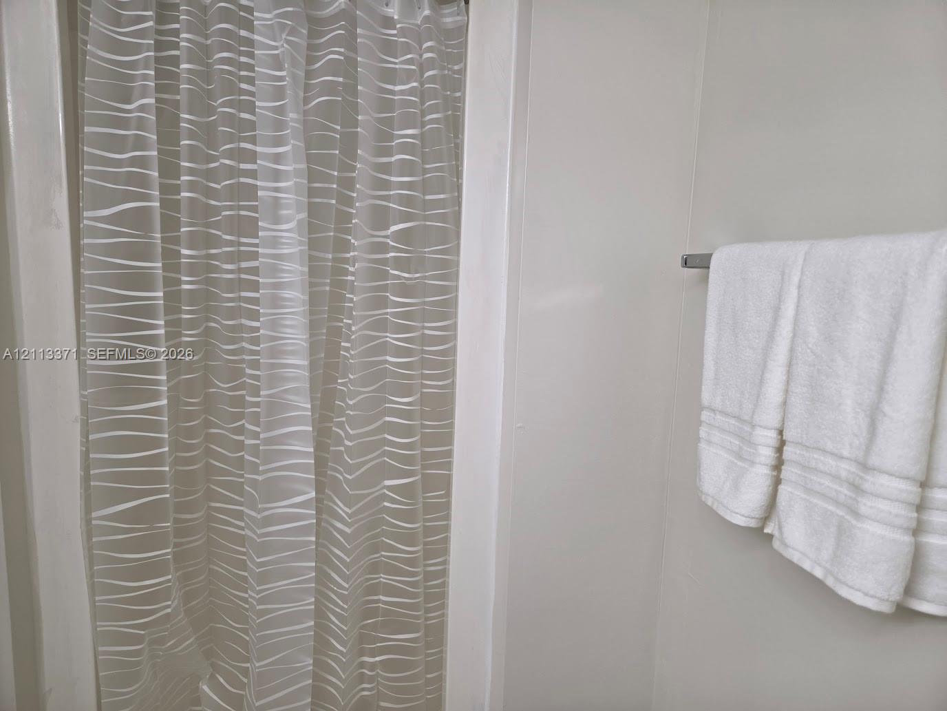 Shower enclosure with seamless wall panels and a mounted metallic towel bar