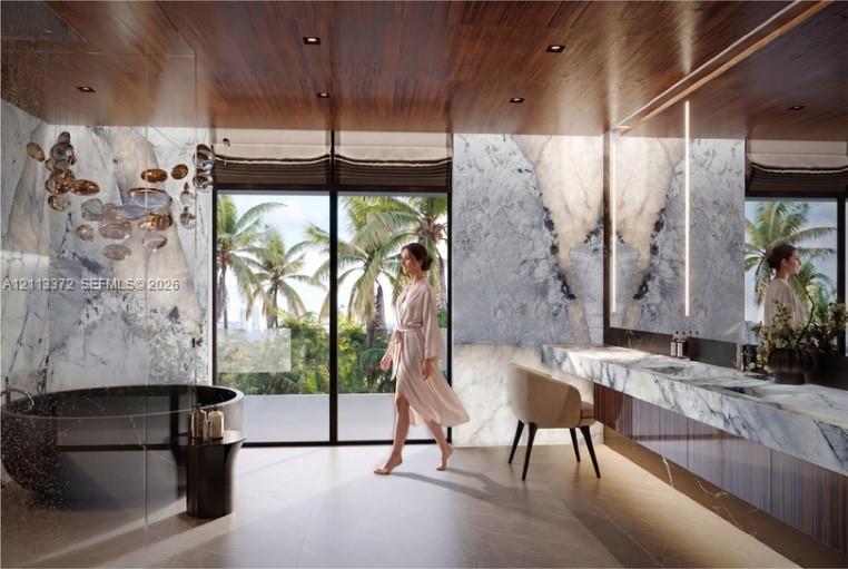Full-height stone wall cladding, floating vanity with dual integrated sinks, freestanding circular soaking tub, floor-to-ceiling glass panel windows, and wood-finish ceiling with recessed lighting