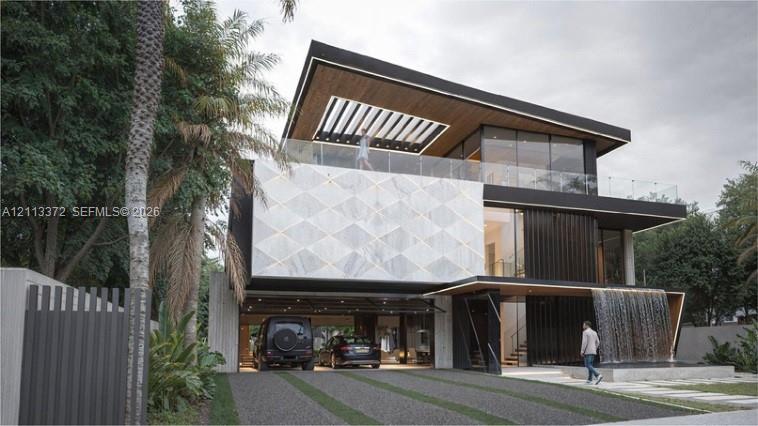 Contemporary multi-level exterior featuring a geometric stone facade, integrated water feature, wood-paneled ceiling overhangs, expansive glass curtain walls, and a glass-railed upper-level terrace