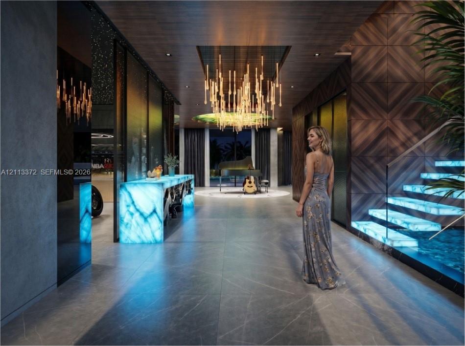 Entry hall featuring large-format tile flooring, illuminated stone accents, wood-paneled walls, custom tiered chandelier, and a floating staircase with glass railings