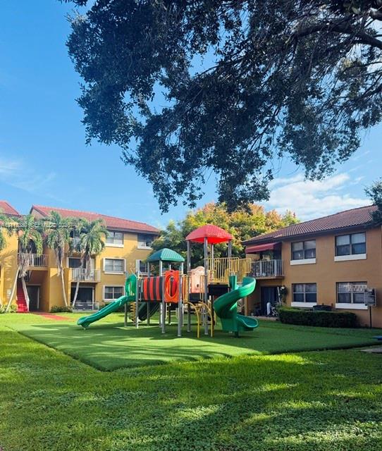 Outdoor recreation area featuring a multi-component play structure with slides and climbing equipment, situated on a manicured lawn with mature trees Outdoor recreation area featuring a multi-component play structure with slides and climbing equipment, situated on a manicured lawn with mature trees