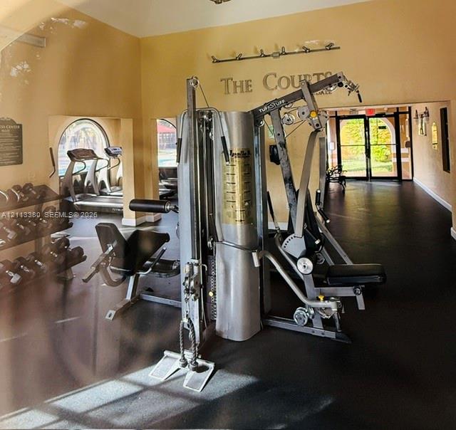 Fitness center featuring rubber flooring, arched windows, and mounted lighting fixtures