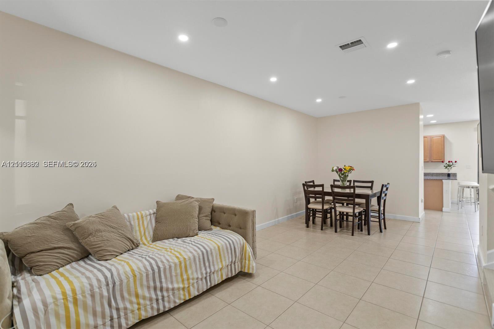 Open-concept interior featuring light-toned floor tile and recessed ceiling lighting
