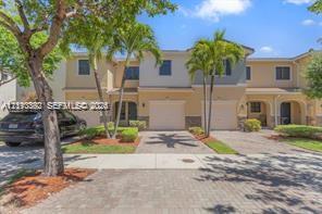 Two-story exterior featuring a paver driveway, attached garage, and multi-tone stucco facade with palm tree landscaping Two-story exterior featuring a paver driveway, attached garage, and multi-tone stucco facade with palm tree landscaping