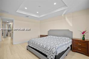 Tray ceiling featuring recessed lighting and light-toned wood-finish flooring