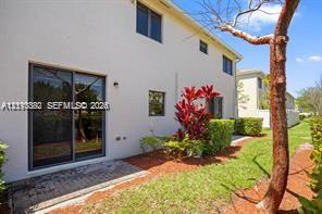 Stucco exterior featuring a sliding glass door, a brick paver patio, and mature landscaping Stucco exterior featuring a sliding glass door, a brick paver patio, and mature landscaping