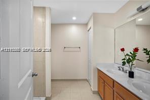 Bathroom featuring a dual-sink vanity with a solid-surface countertop, full-width mirror, tile flooring, and a tiled shower enclosure Bathroom featuring a dual-sink vanity with a solid-surface countertop, full-width mirror, tile flooring, and a tiled shower enclosure