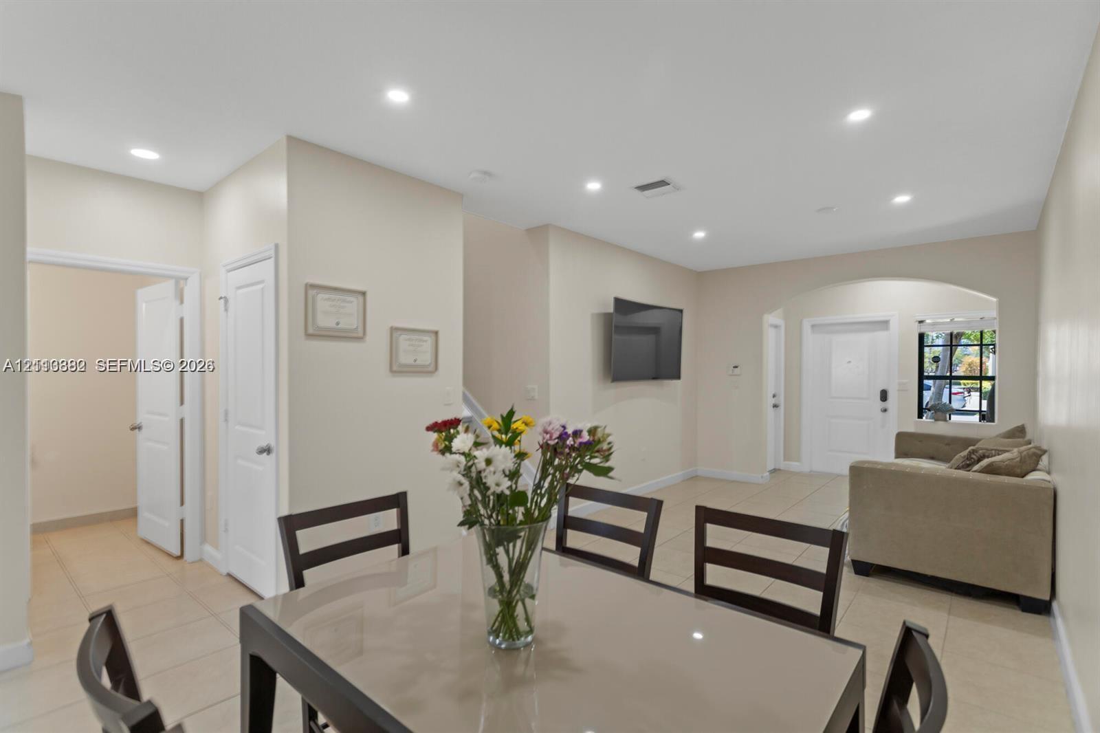 Open-concept area featuring neutral wall paint, tile flooring, recessed ceiling lighting, and an arched entryway Open-concept area featuring neutral wall paint, tile flooring, recessed ceiling lighting, and an arched entryway
