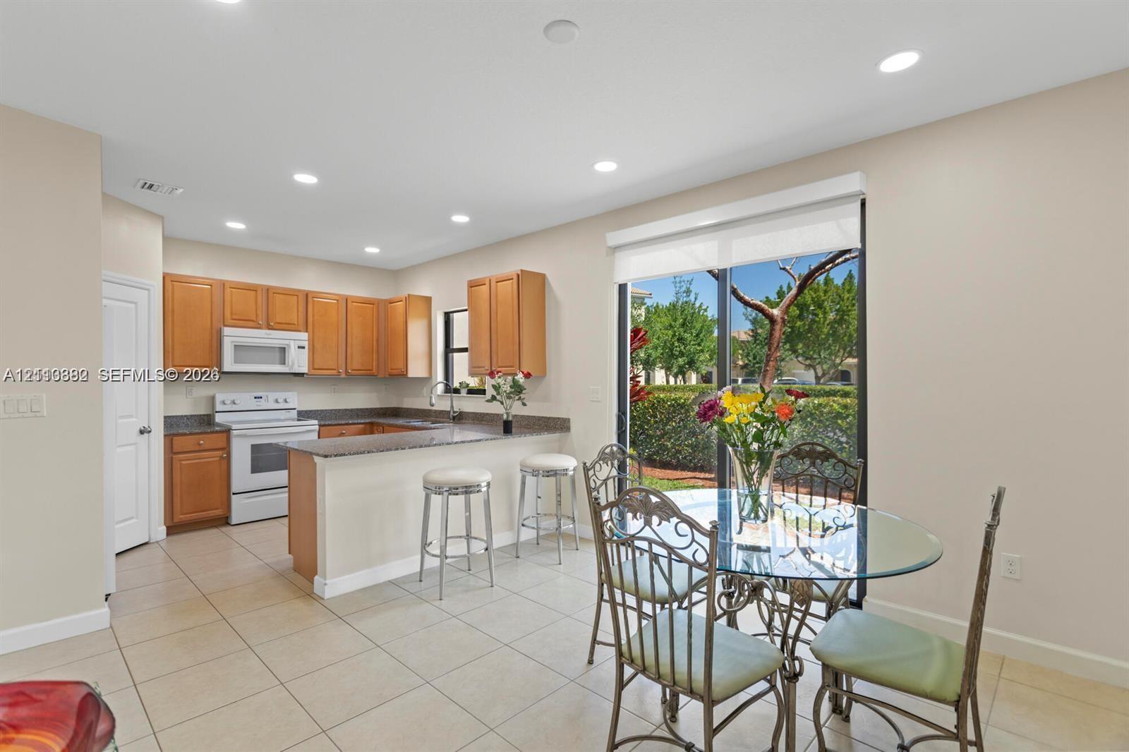 Kitchen featuring wood cabinetry, stone-finish countertops, recessed lighting, tile flooring, and a sliding glass door