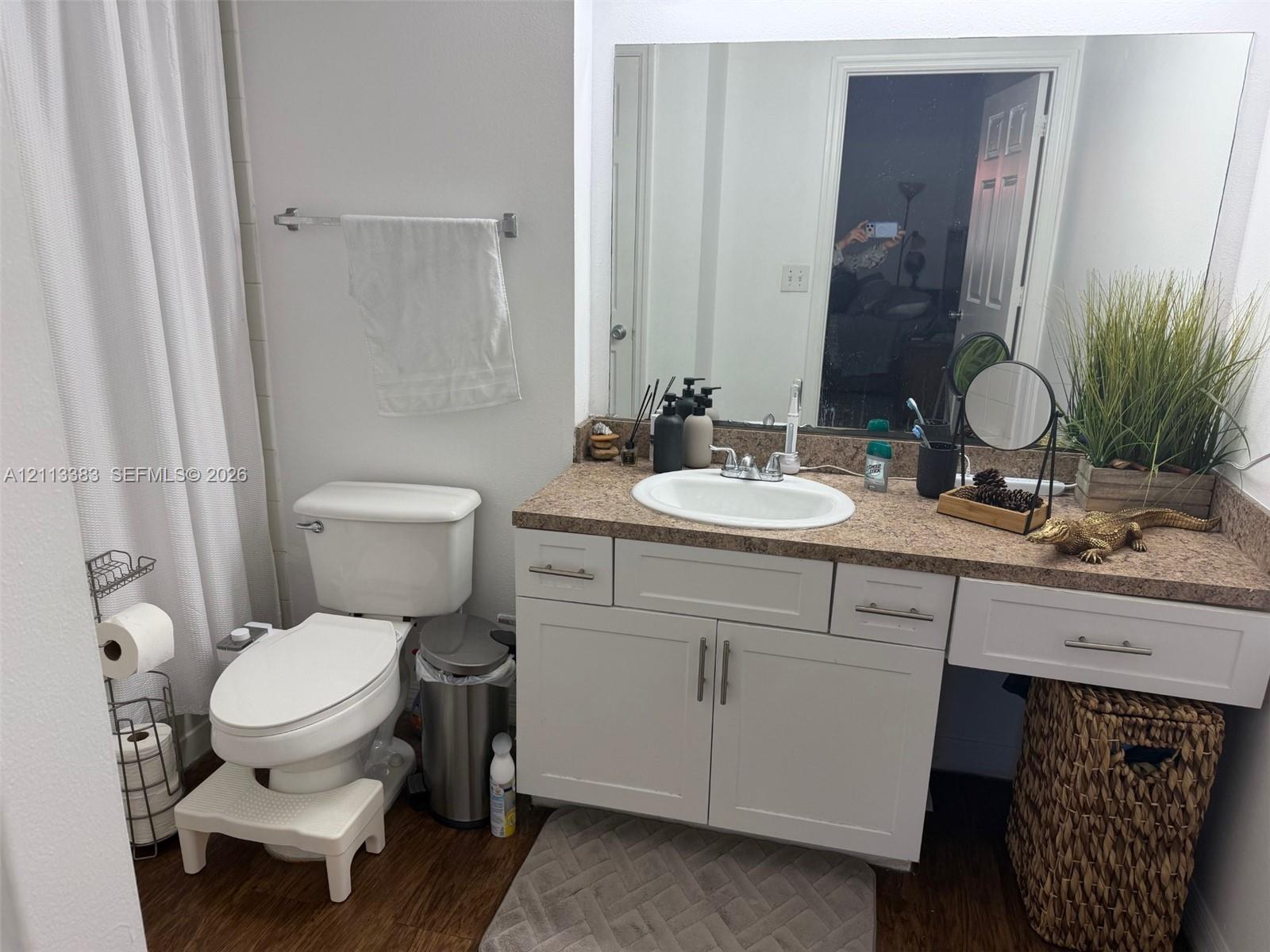 Bathroom featuring a white vanity cabinet with shaker-style doors, an integrated countertop with an oval drop-in sink, and a large frameless wall-mounted mirror