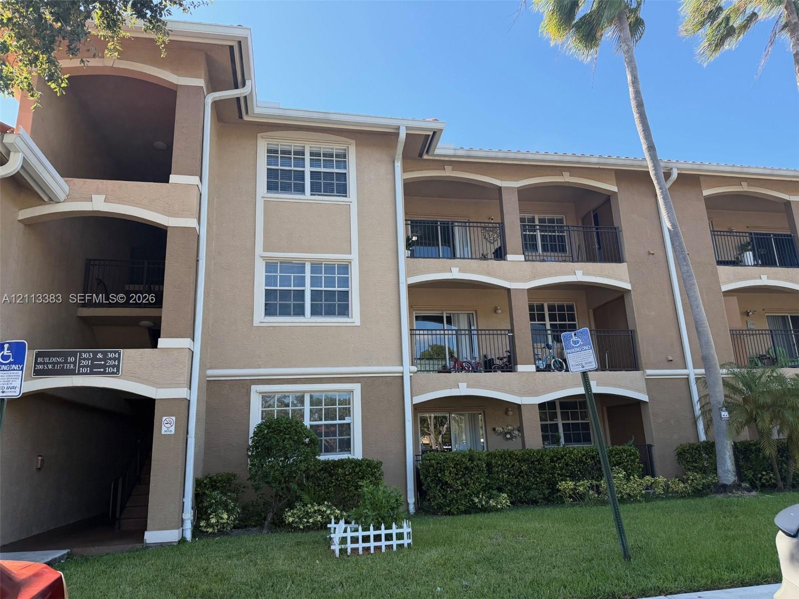 Stucco exterior featuring multi-level arched balconies, metal railings, and manicured landscaping