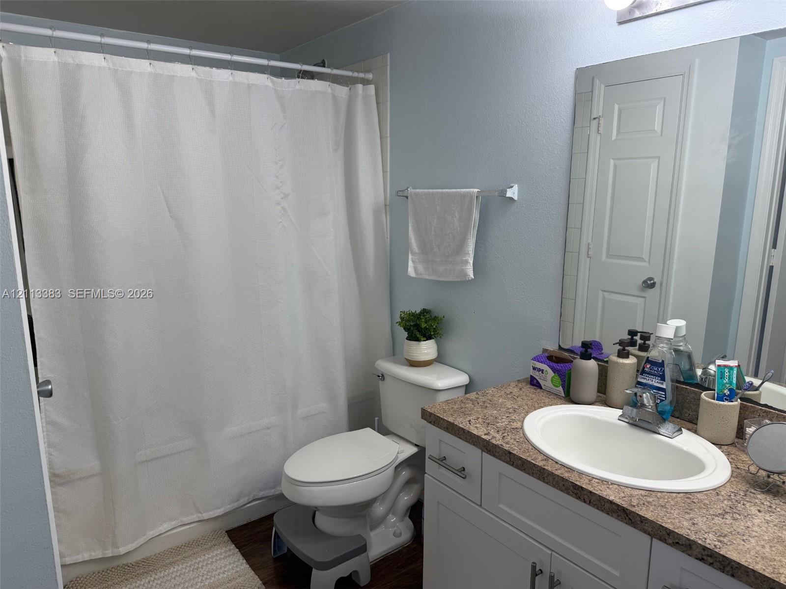 Bathroom featuring a stone-pattern laminate countertop, white vanity cabinetry, integrated oval sink, chrome faucet, and a tiled tub-shower surround