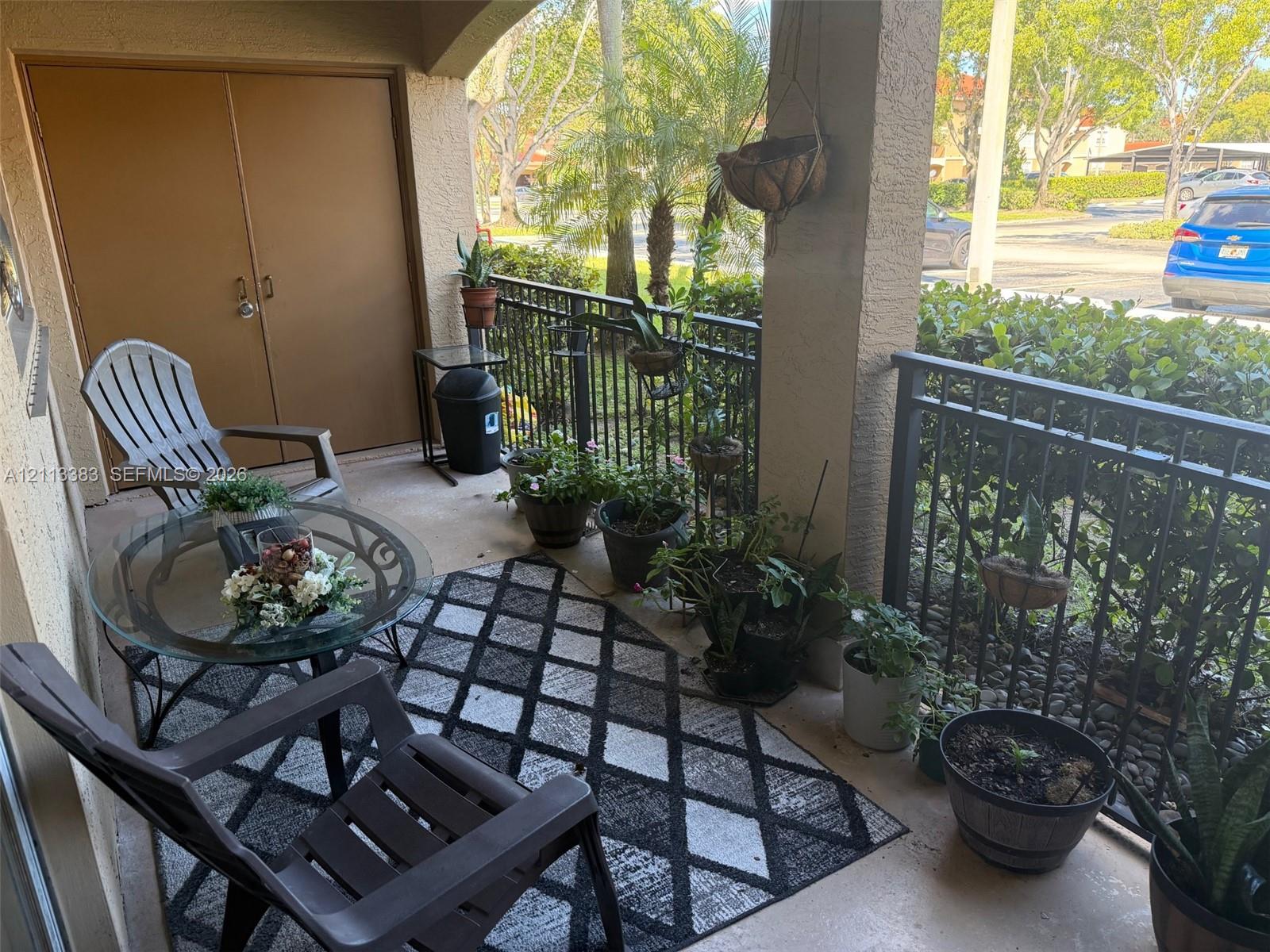 Covered balcony featuring concrete flooring, a lockable storage closet, and black metal railings