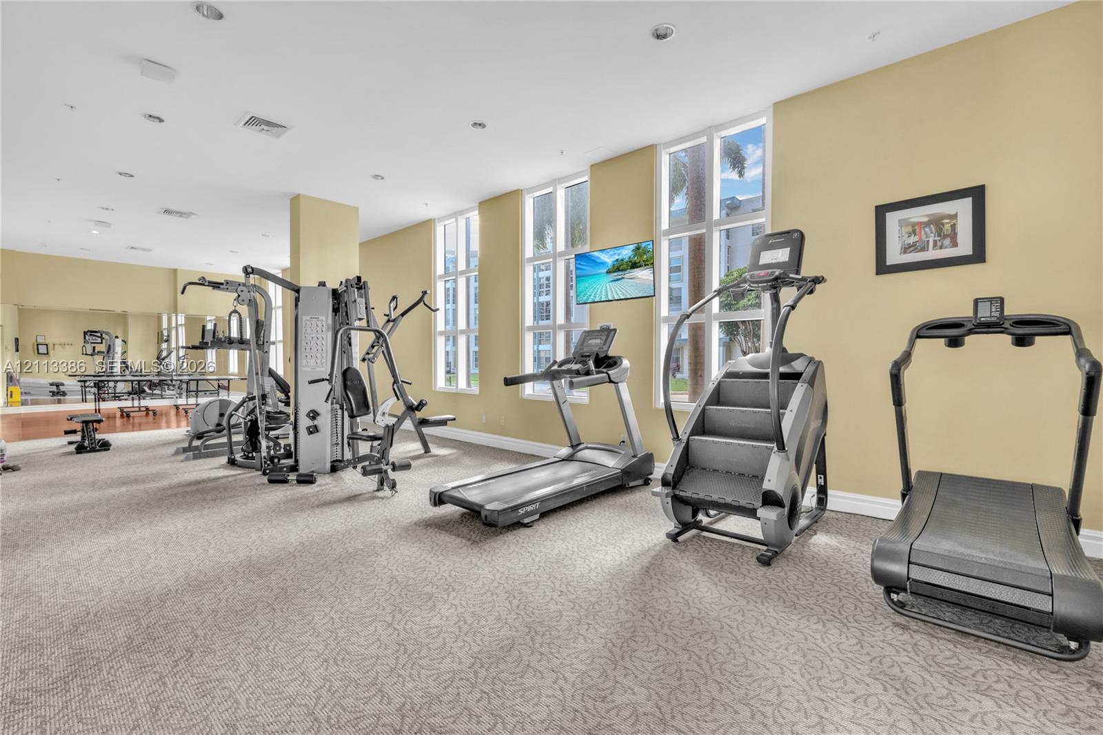 Fitness center featuring wall-to-wall mirrors, floor-to-ceiling windows, and recessed lighting