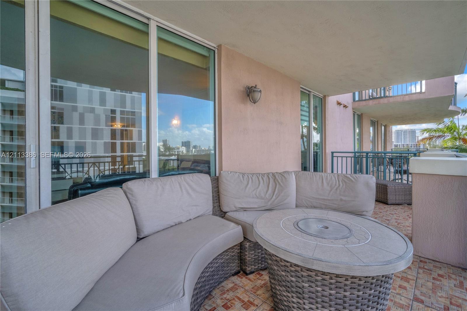 Covered balcony featuring floor-to-ceiling glass sliding doors, stone-tiled flooring, and metal railing