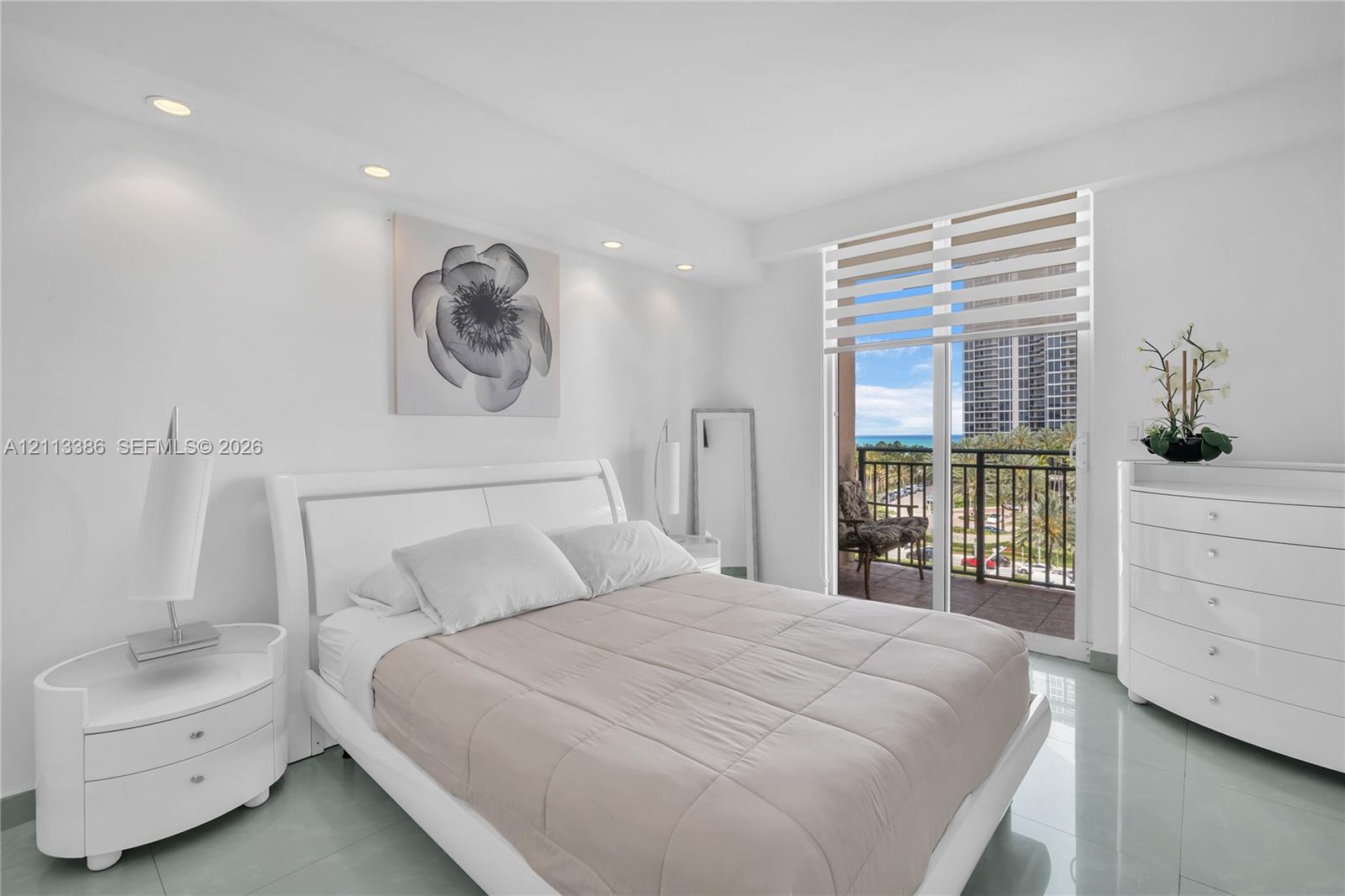 Sleek tile flooring, recessed ceiling lighting, and sliding glass doors opening to a private balcony with an exterior railing