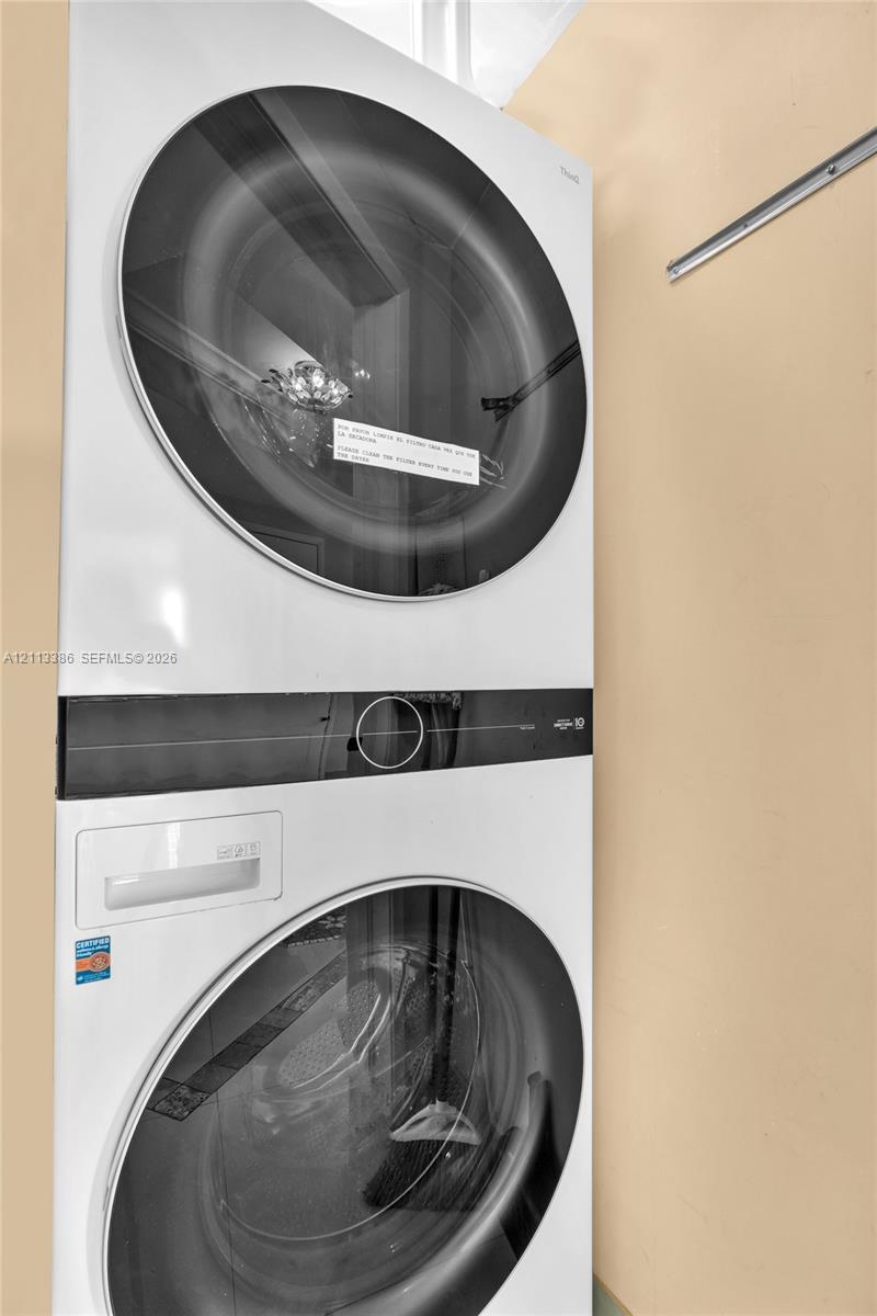 Stacked white front-load washer and dryer unit featuring glass-front doors and digital touch-control panels