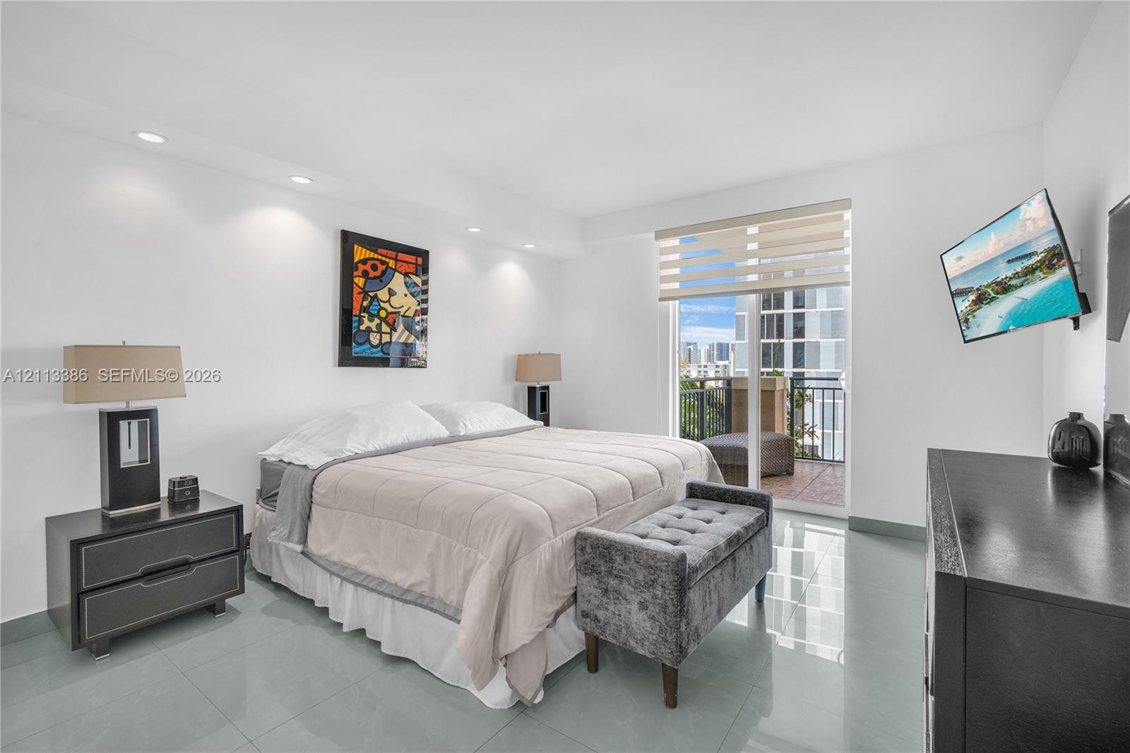 Recessed ceiling lighting, large-format tile flooring, and sliding glass door access to a private balcony