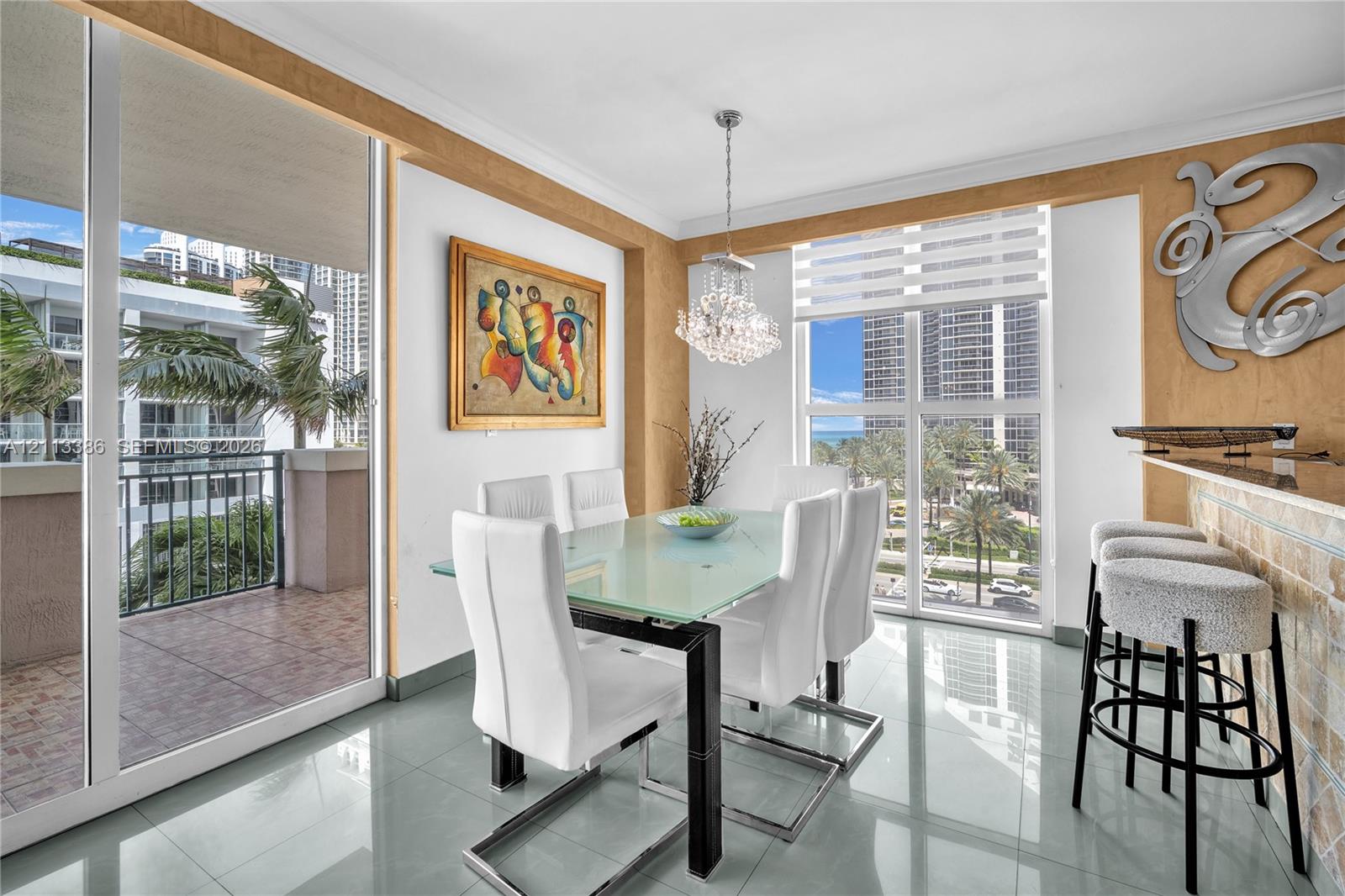 Dining area featuring polished tile flooring, floor-to-ceiling windows, a stone-accented breakfast bar, and a crystal chandelier