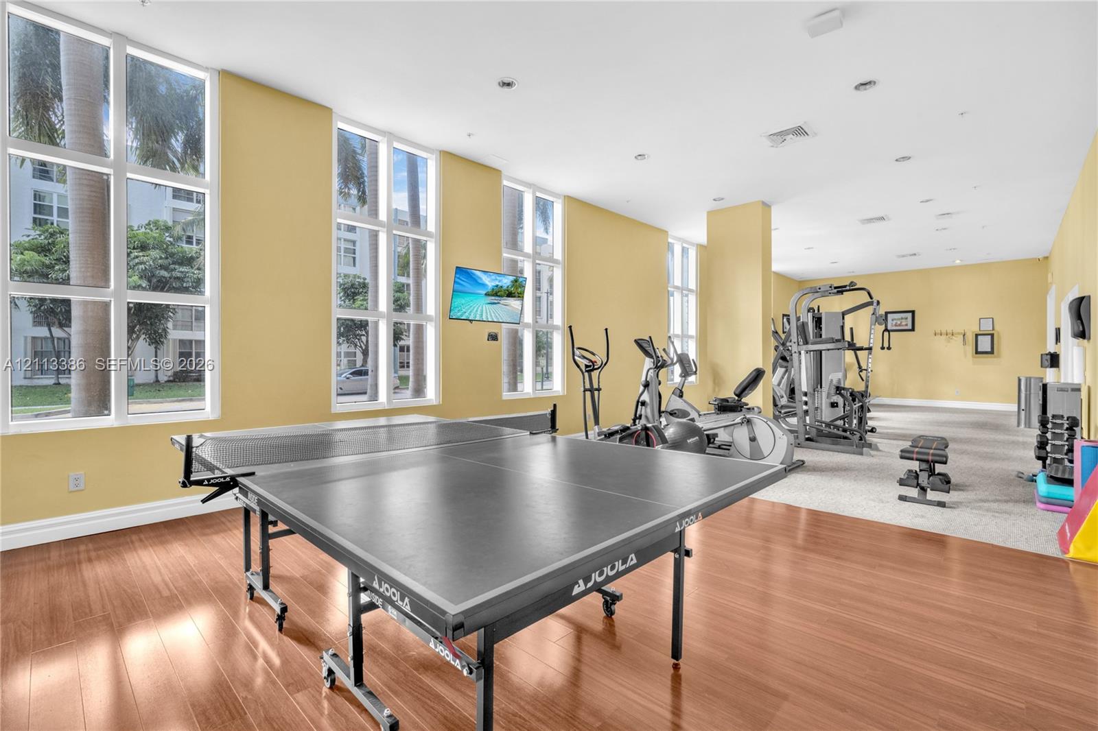 Fitness center featuring floor-to-ceiling windows, wood-finish flooring, and recessed ceiling lighting