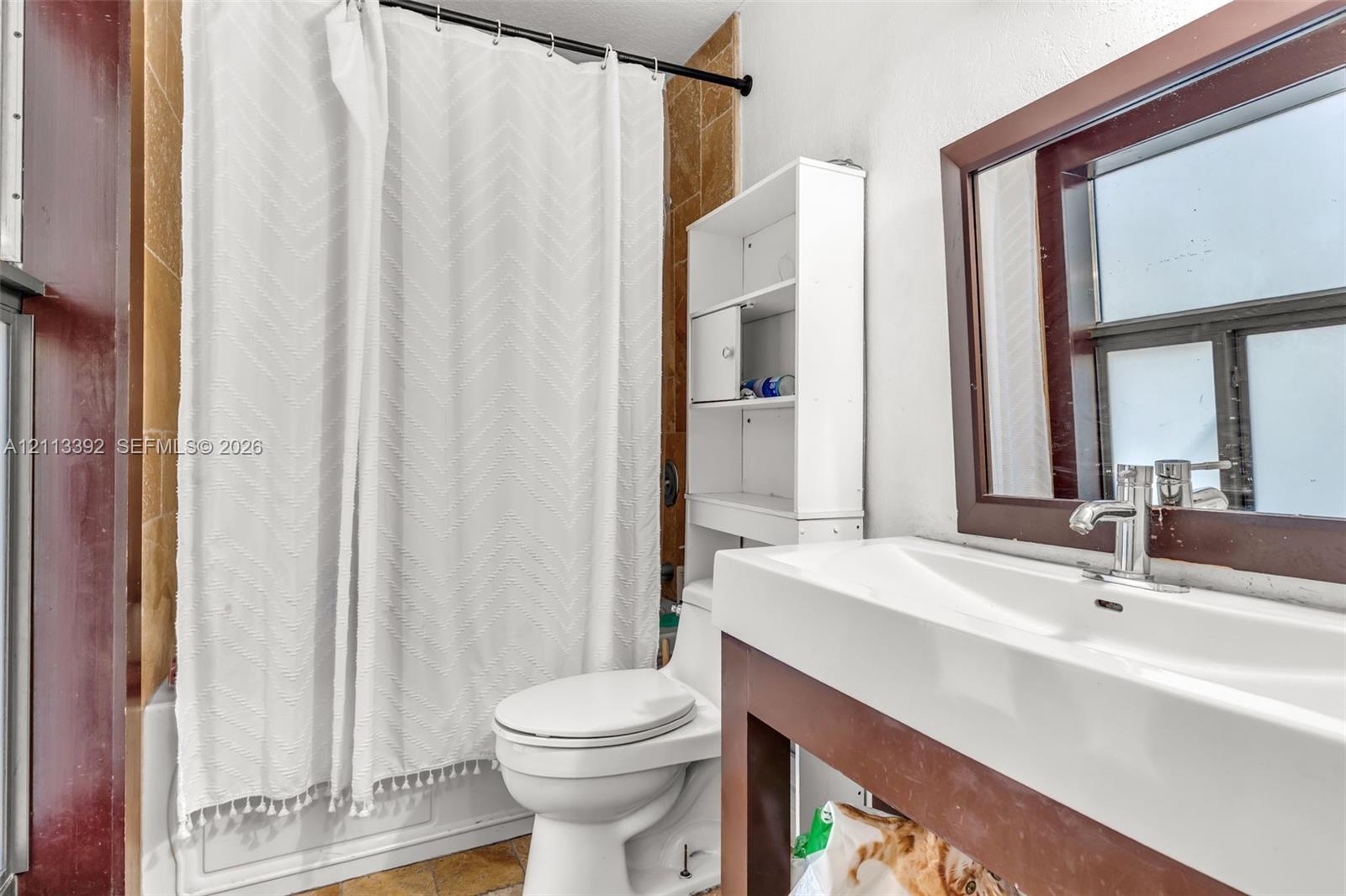 Bathroom featuring a vanity with a rectangular sink, a metal faucet, a framed mirror, and a tub surround with tiled wall cladding