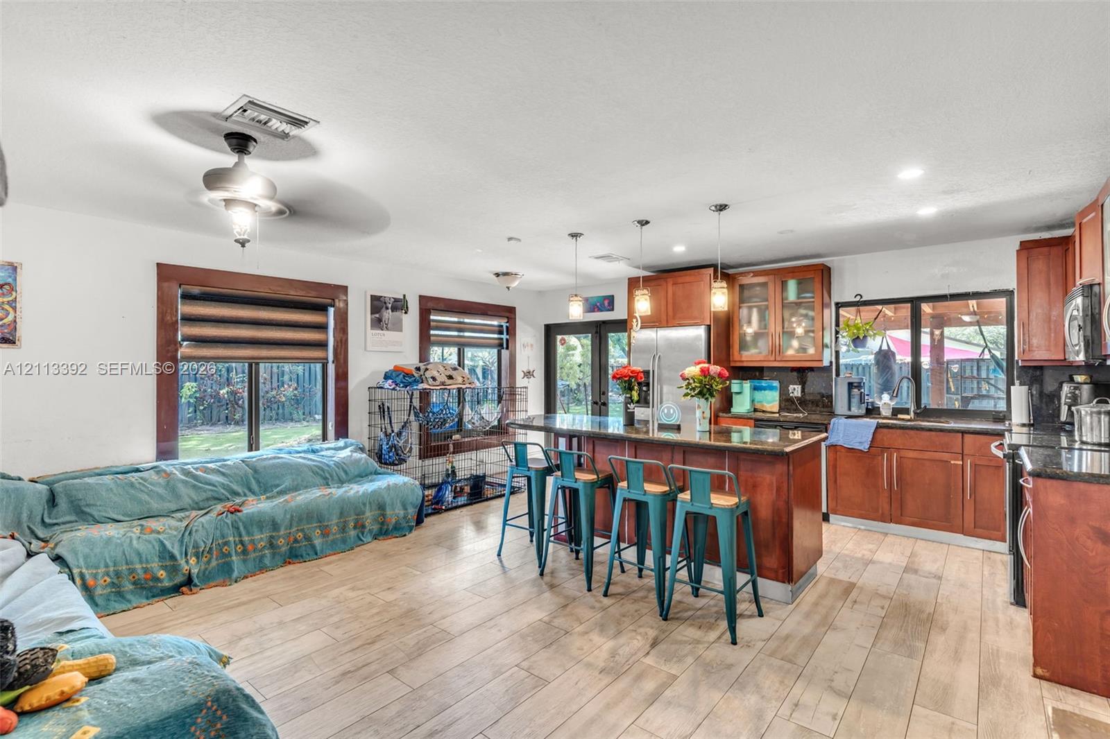 Kitchen featuring wood cabinetry, stone countertops, a center island with pendant lighting, and wood-finish flooring