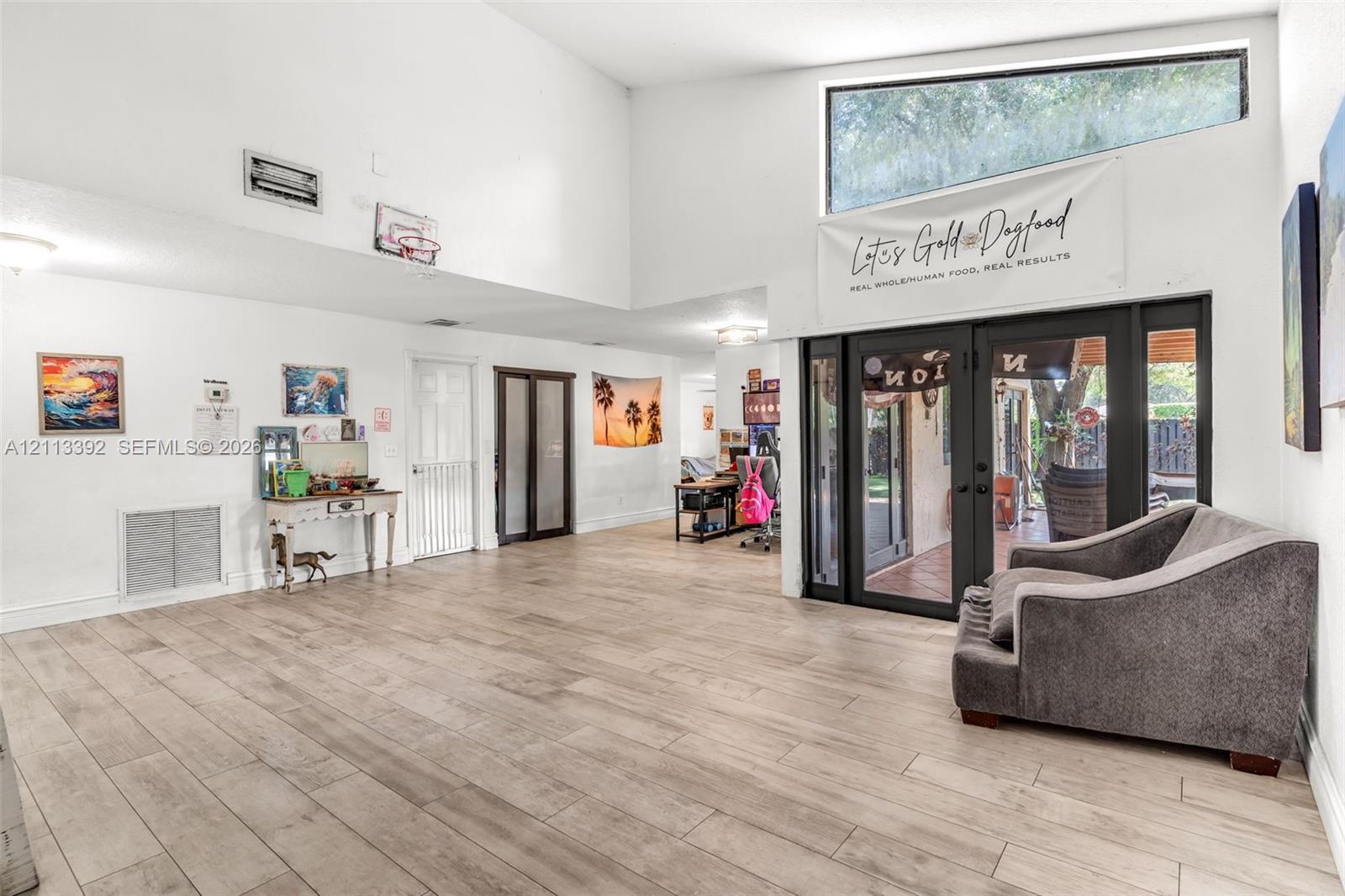 Vaulted ceilings featuring wood-finish flooring, recessed lighting, and expansive glass-paneled double doors with a trapezoidal clerestory window