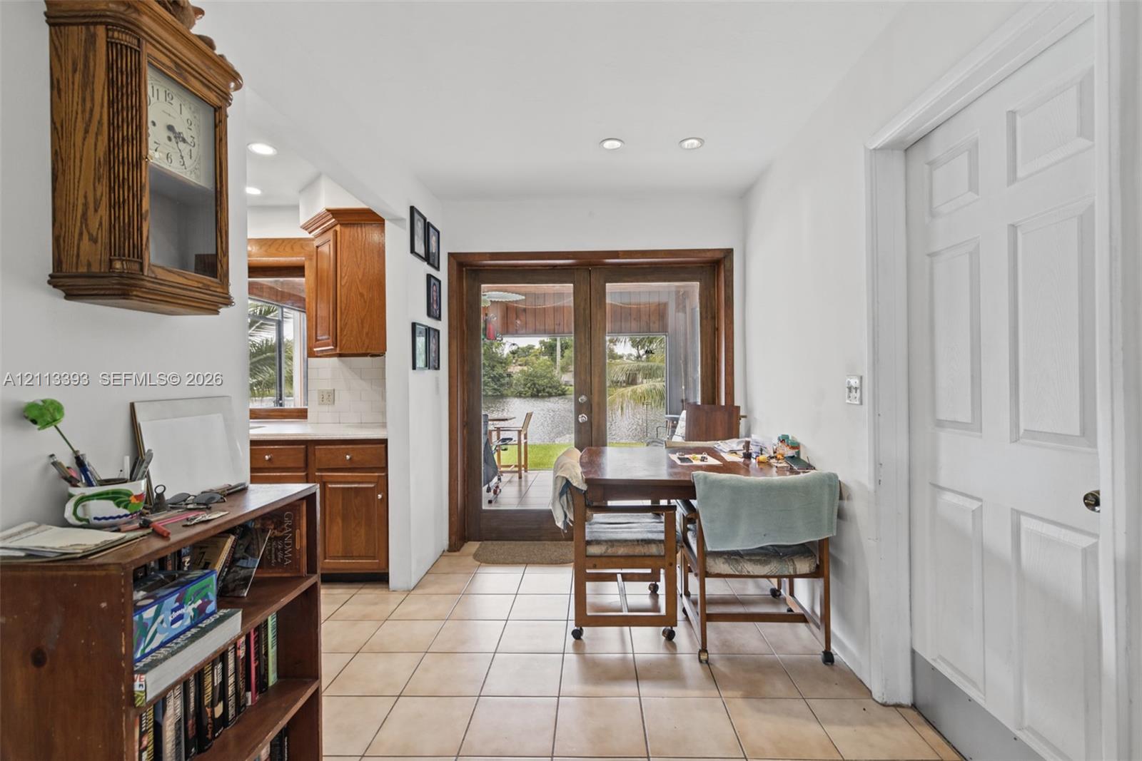 Ceramic tile flooring, wood-framed French doors, and recessed lighting, with wood cabinetry visible in the background