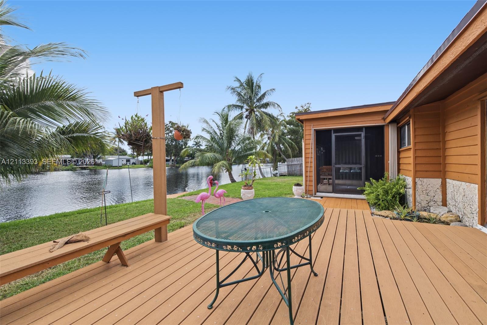 Waterfront outdoor space featuring a wood-finish deck, integrated bench seating, a screened-in porch, and direct bulkhead access